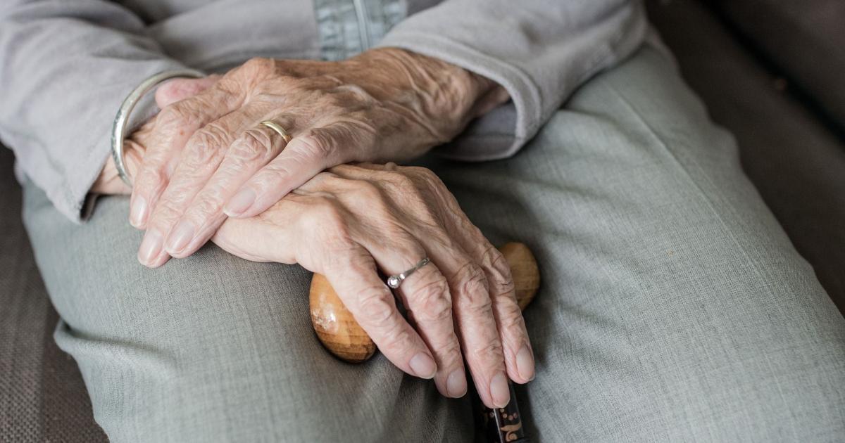 Una persona de avanzada edad sostiene un bastón