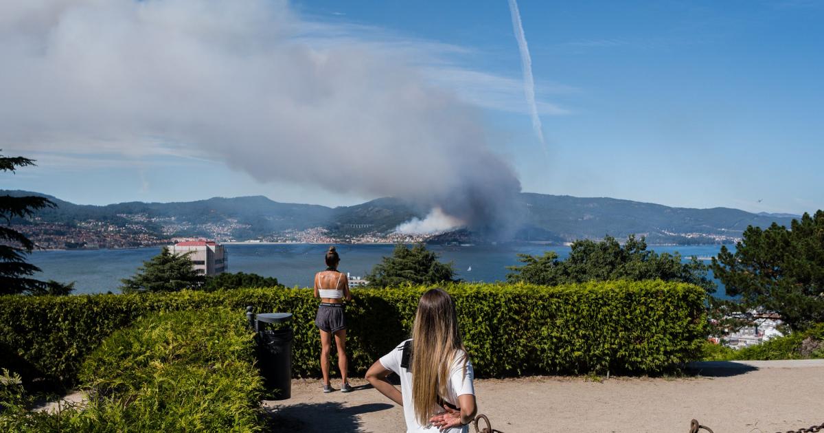 Dos jóvenes observan una columna de humo desde Vigo, tras el incendio declarado en Moaña (Pontevedra).