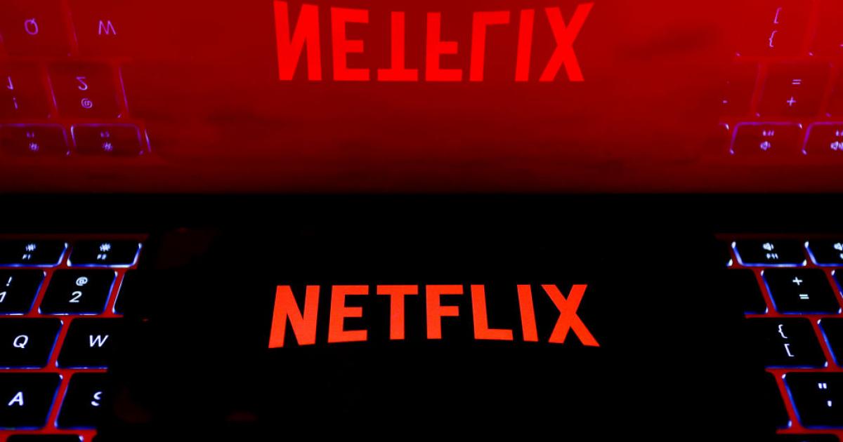 Logotipo de Netflix en la pantalla de un móvil reflejado en la de un portátil