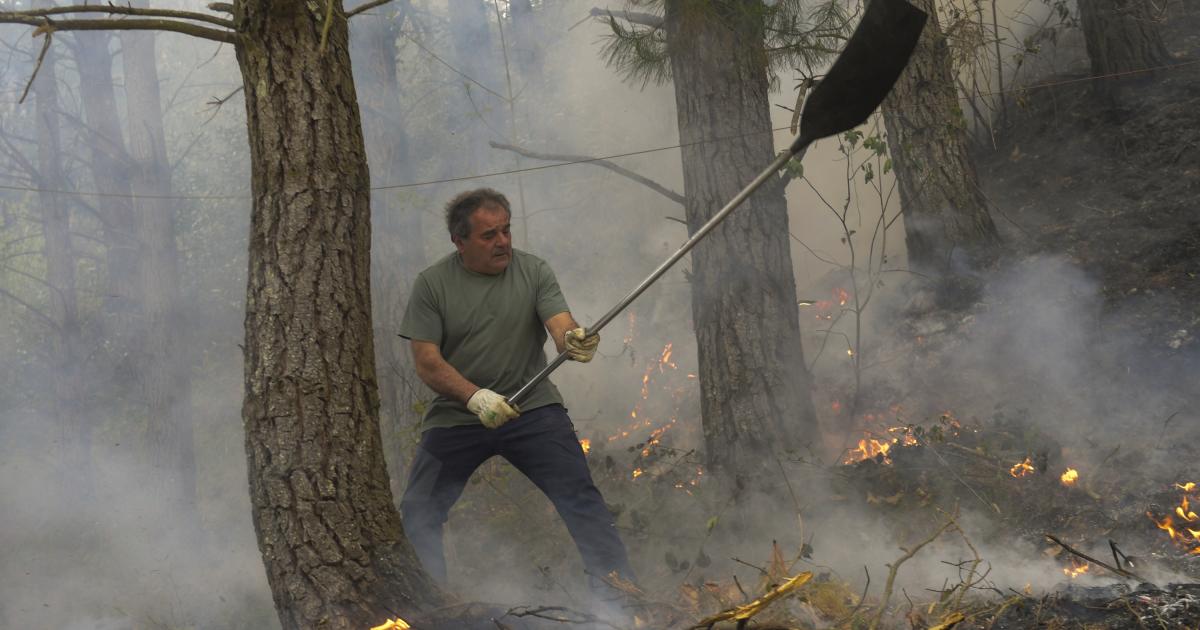Un hombre trabaja en las labores de extinción del incendio declarado en Navelgas, Asturias.