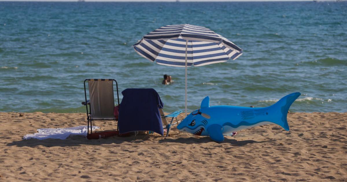 Un flotador con forma de tiburón junto a una silla y una sombrilla de playa en Palma de Mallorca en una foto de 2020.
