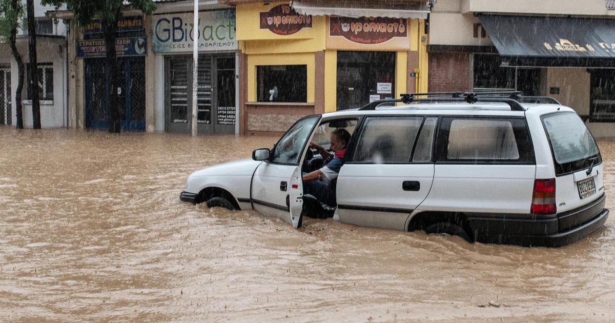 Un hombre trata de salir de su vehículo al verse sorprendido por la riada en la capital de la región griega de Magnesia, Volos.