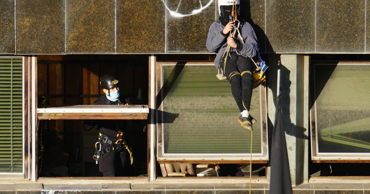 GRAFCAT6961. BARCELONA, 30/11/2023.- Un agente conversa con una ocupa que permanece colgada de la fachada después de que los Mossos hayan conseguido acceder al interior de El Kubo, uno de las dos casas ocupadas en la Bonanova de Barcelona que deben ser desalojadas este jueves, y están en estos momentos inspeccionando las plantas subterráneas y realizando gestiones para asegurar el acceso a las superiores, así como al patio de la Ruïna. Los agentes desplegados en el lugar se están encontrando con una fuerte resistencia de los ocupas, que se han atrincherado para evitar ser desalojados, y desde el interior de las casas, que están comunicadas entre sí, los ocupas han lanzado sacos de escombros, botes de humo y bengalas para dificultar la intervención.