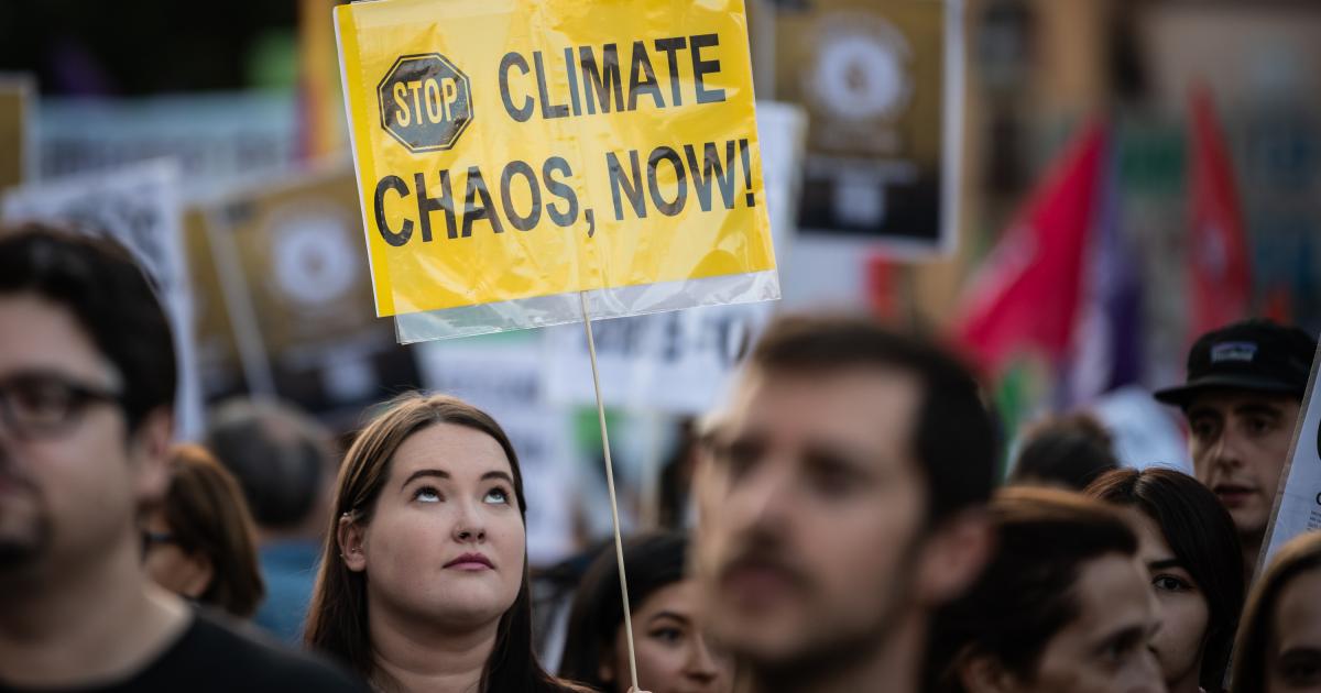 Un joven con una pancarta que pide parar el "caos climático, ya".