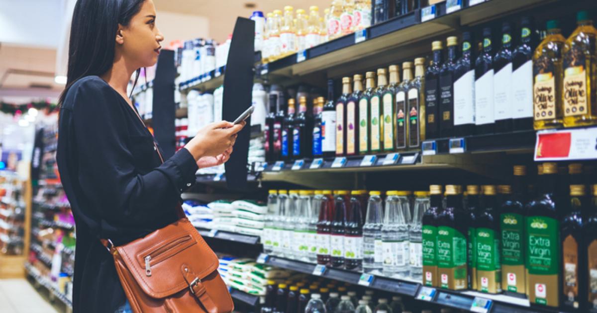 Imagen de una mujer comprobando varias marcas de aceite de oliva en un supermercado.