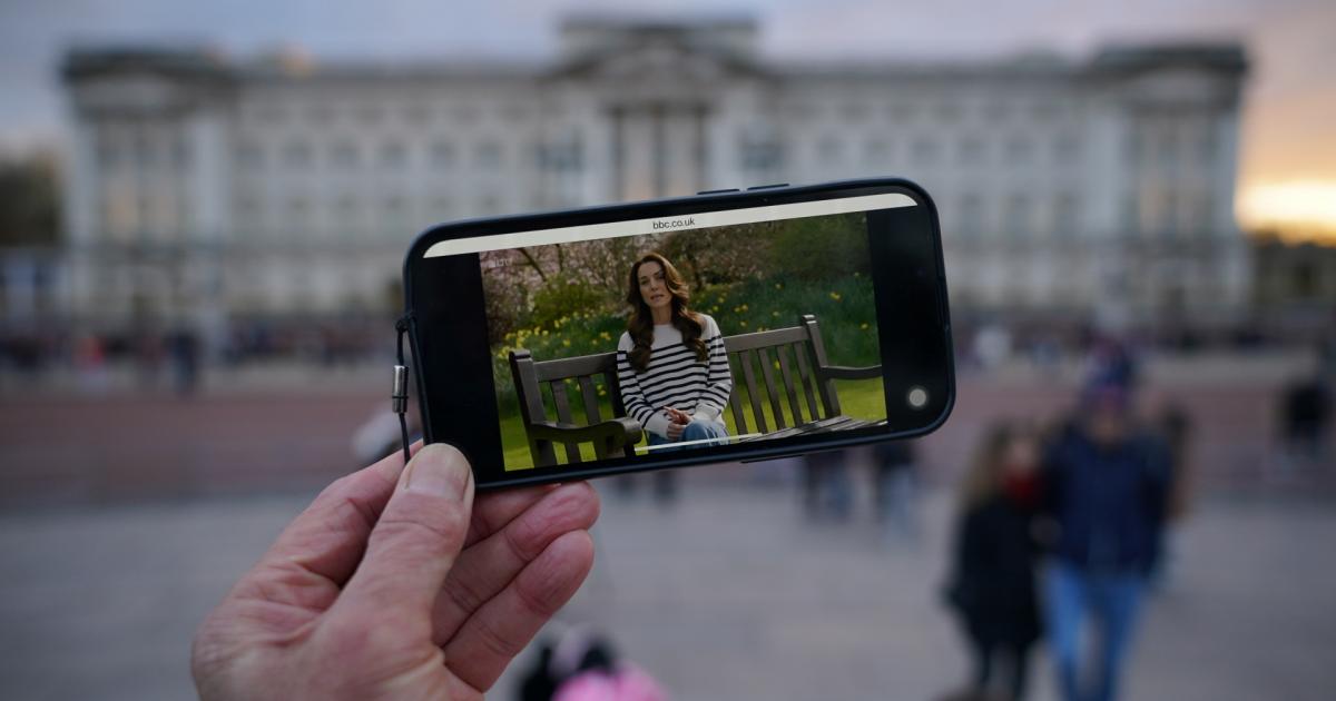 Una persona viendo el anuncio de Kate Middleton frente al palacio de Buckingham.