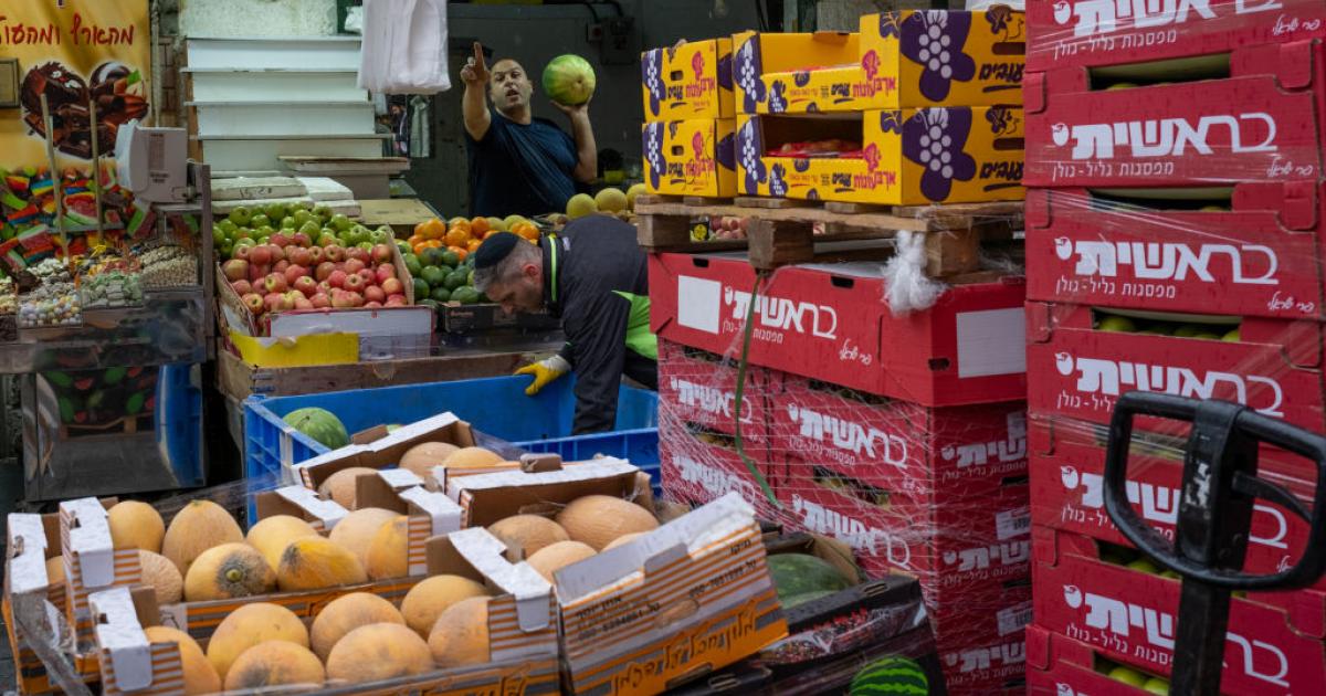 Trabajadores del mercado de Mahane Yehuda, Jerusalén, reponen productos en su puesto.