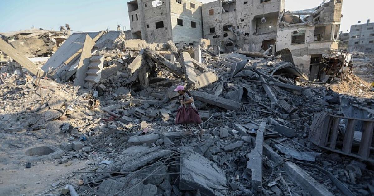 Imagen de archivo de una niña caminando con escasas pertenencias entre los restos de edificios bombardeados por el Ejército de Israel, en la Franja de Gaza.