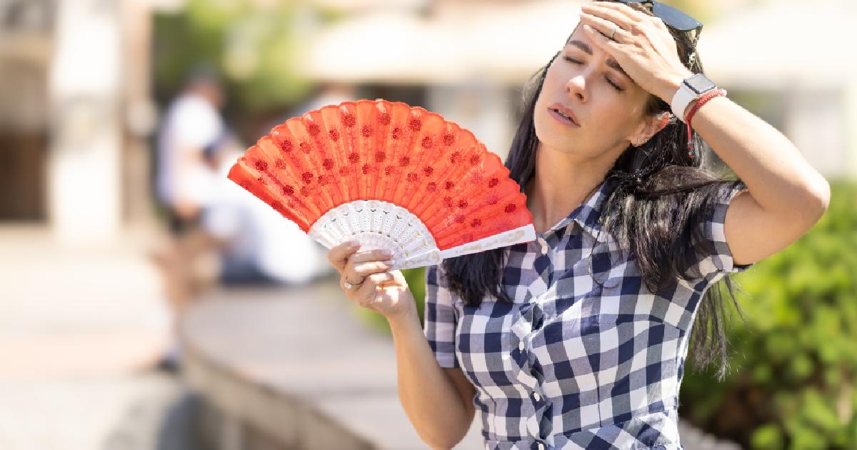 Una mujer abanicándose por el calor.