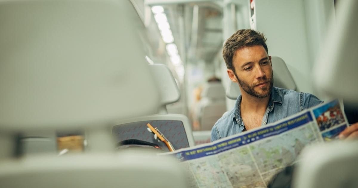 Un turista consulta un mapa de de España mientras viaja en tren.