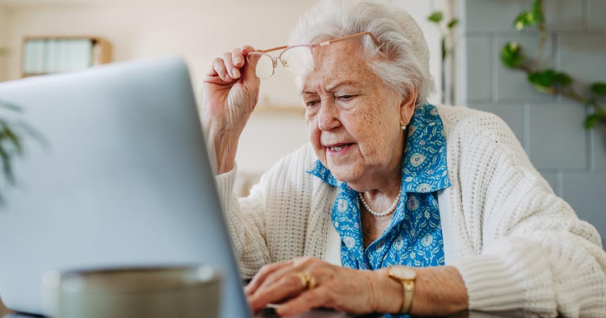 Imagen de archivo de una señora mayor comprobando algo en su portátil.