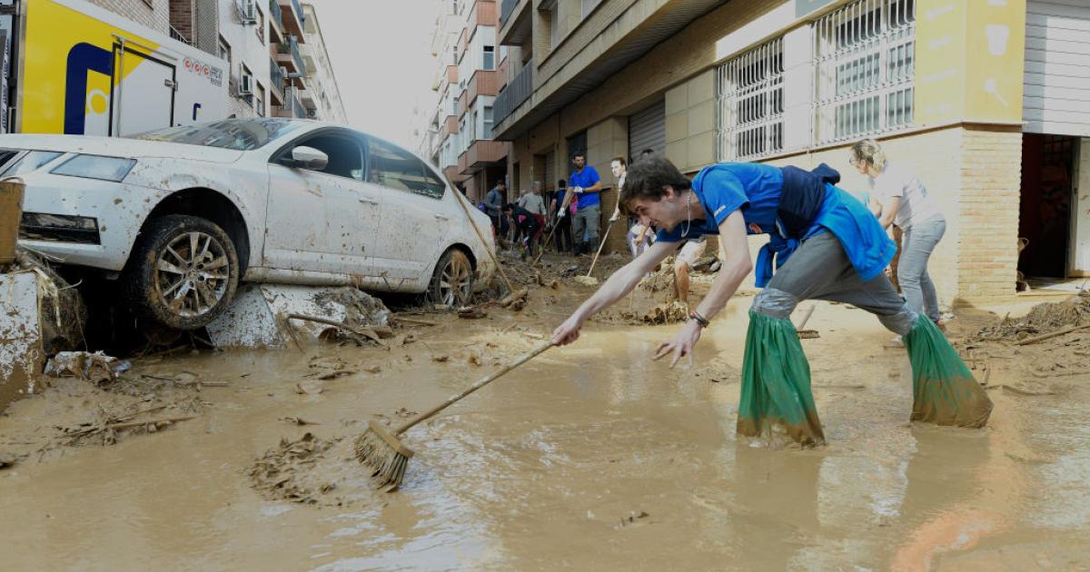 Una voluntaria limpia el barro en las calles de Paiporta.