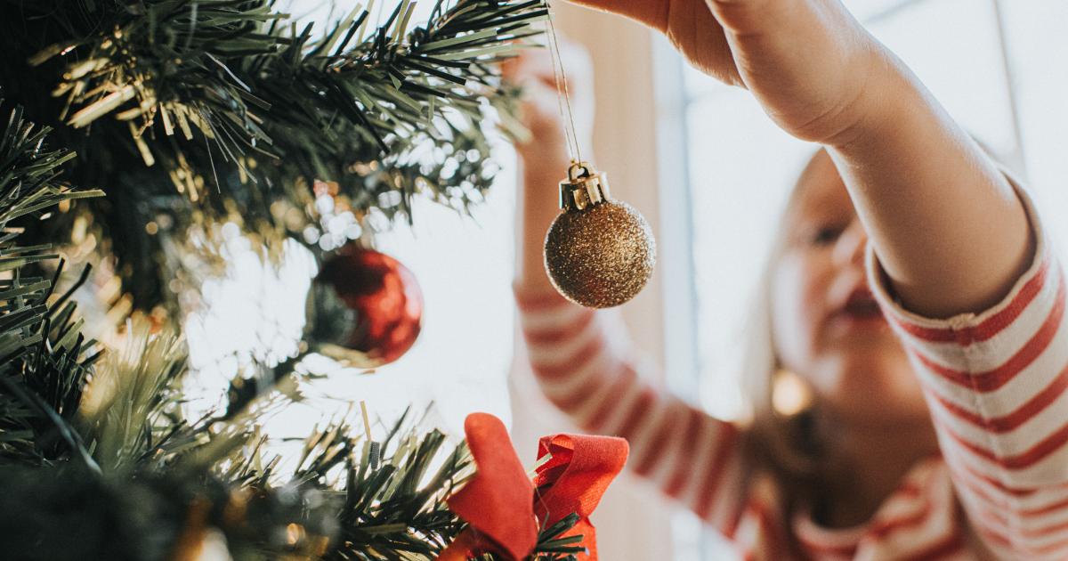 Una niña decorando un árbol de Navidad.