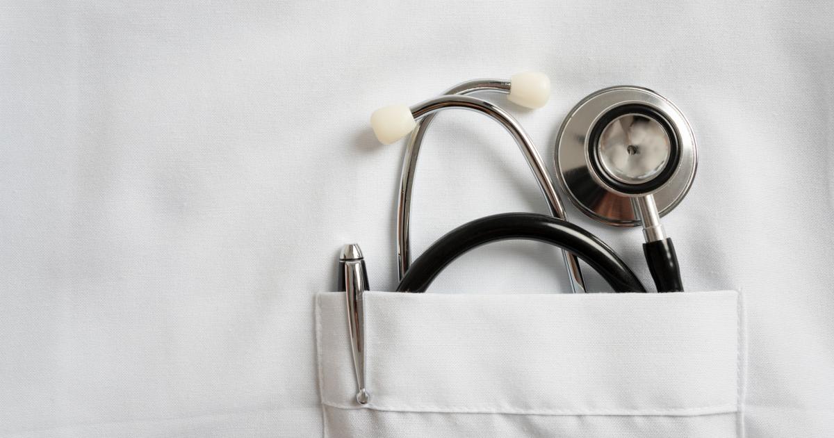 Imagen de un detalle de un fonendoscopio y un bolígrafo en el bolsillo de la bata de un médico.