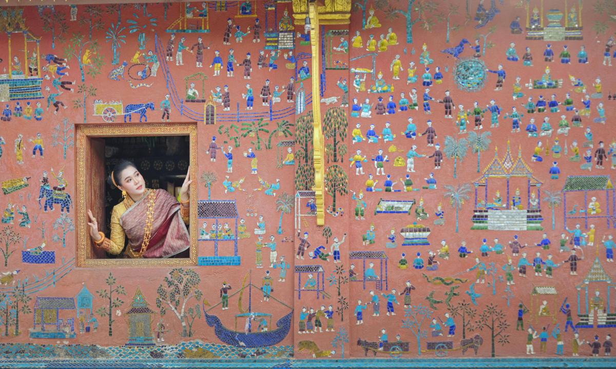 Una mujer asomada por la ventana de un templo en Wat Xieng Thong, Luang Prabang, Laos.