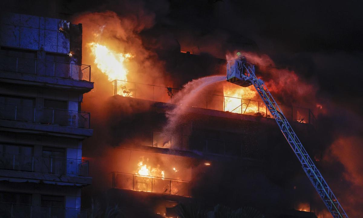 Los bomberos trabajan en la extinción del incendio en el edificio de 14 plantas en Valencia