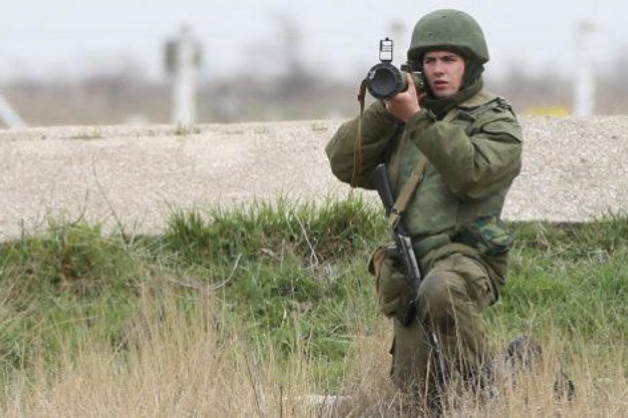 LUBIMOVKA, UKRAINE - MARCH 04:  A soldier under Russian command aims a rocket propelled grenade launcher at a group of over 100 hundred unarmed Ukrainian troops who appeared at the Belbek airbase, which the Russian troops are occcupying, in Crim...