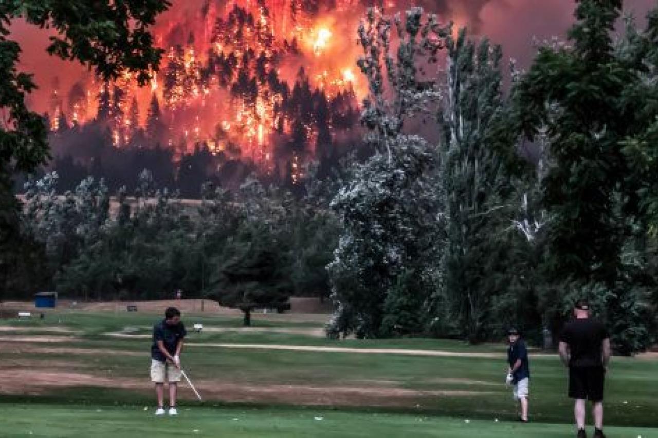El bosque de Eagle Creek arde mientras varios golfistas juegan en el Campo de Golf Beacon de North Bonneville, en Washington, EEUU, el 4 de septiembre de 2017.
