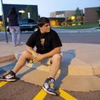 Eyewitness Chandler Brannon, 25, sits outside Gateway High School where witnesses were brought for questioning after a shooting at a movie theater showing the Batman movie "The Dark Knight Rises," Friday, July 20, 2012 in Aurora. A gunman weari...