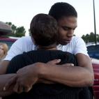 Eyewitness Isaiah Bow hugs his mother Shamecca Davis after being questioned by police outside Gateway High School where witnesses were brought in, Friday, July 20, 2012 in Aurora, Colo. After leaving the theater Bow went back in to find his gir...