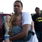 Judy Goos, second from left, hugs her daughters friend, Isaiah Bow, 20, while eye witnesses Emma Goos, 19, left, and Terrell Wallin, 20, right, gather outside Gateway High School where witness were brought for questioning Friday, July 20, 2012 ...