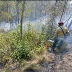 Un bombero enciende un cortafuegos en un bosque entre las localidades de Boadella y Terrades