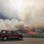 Un vehículo de emergencias pasa junto a las llamas.