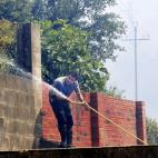 Un vecino de la localidad de La Jonquera remoja las paredes de su propiedad tras acercarse las llamas.