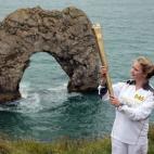 JULY 13: Torchbearer Lisa Devine holds the Olympic Flame in front of Durdle Door, during Day 56 of the London 2012 Olympic Torch Relay on July 13, 2012 in Dorset, England. The Olympic Flame is now on day 56 of a 70-day relay involving 8,000 torc...