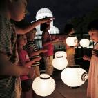 Un grupo de niños sostiene lámparas de papel mientras rezan junto al Parque de la Paz de Hiroshima en recuerdo a las víctimas en el 67 aniversario de la explosión nuclear.