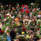 Una bandera noruega ondea entre las más de cien mil personas reunidas en Oslo durante la vigilia en recuerdo de las víctimas de la matanza.