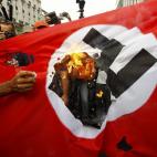 Un manifestante queda una bandera nazi en protesta por la visita de Merkel a Atenas.