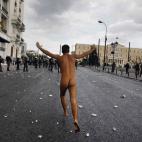 Un protestante corre por las calles de Atenas como vino al mundo.