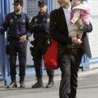 Un ciudadano chino pasa ante agentes de la Policía Nacional durante el registro a negocios del polígono industrial Cobo Calleja.