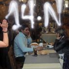 A protestor shouts as a couple eat inside a open restaurant during a general strike in Madrid, Spain, Wednesday, Nov. 14, 2012. Spain's main trade unions stage a general strike, coinciding with similar work stoppages in Portugal and Greece, to p...