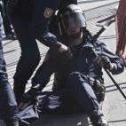 A police officer, right, is helped by a colleague after getting hurt during a general strike in Madrid, Wednesday Nov. 14, 2012. A Spanish Interior Ministry official says 32 people have been arrested and 15 people treated for minor injuries in d...