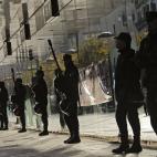 Spanish riot policemen stand in a line against the window of a bank during a general strike against government austerity measures, in Pamplona, northern Spain, Wednesday, Nov. 14, 2012. A Spanish Interior Ministry official says 32 people have be...