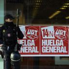 A Spanish riot police officer stands beside posters that read: "14 November, General Strike" calling for a general strike against government austerity measures, in Pamplona, northern Spain, Wednesday, Nov. 14, 2012. A Spanish Interior Ministry o...
