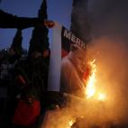 People burn a picture of German Chancellor Angela Merkel during a protest against her visit to Portugal outside Lisbon's Belem Cultural Center where Merkel was participating in a business conference attended by leading German and Portuguese comp...