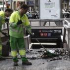  Operarios de limpieza retiran restos de un pequeño incendio en las puertas del metro Universitat, en Barcelona.