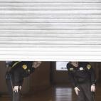 Agentes privados de seguridad miran hacia la calle desde el interior de una empresa, en el centro comercial Triangle de plaza Catalunya, en Barcelona.