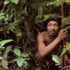 Un hombre descansa en la selva tras una expedición de caza. Muchas familias salen en partidas de caza que duran varias semanas: duermen en refugios hechos con hojas de palmera