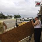 Dos hombres transportan un panel de madera para proteger un edificio de Gulfport (Misisipi), ante la llegada de la tormenta.