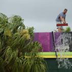 Un hombre quita el agua del tejado de su local con ayuda de una escoba, después de las intensas lluvias que han caído sobre Tampa, Florida (EEUU)