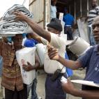 Un residente recibe ayuda de la Organización Internacional para las Migraciones (OIM) en un campamento para personas desplazadas en Puerto Príncipe, 26 de agosto de 2012.