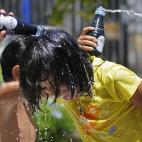 Un grupo de niños aprovecha el calor sevillano para jugar y refrescarse con agua