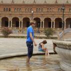 Unos turistas se refrescan en una fuente de la Plaza de España en Sevilla