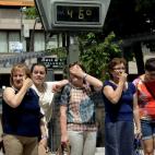 Unas mujeres sufren la ola de calor ante un termómetro al sol que marca 46 grados, en el centro de la ciudad gallega de Ourense.