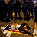 Un manifestante se tumba en una estelada junto a los Mossos d'Esquadra a las puertas de la Conseller&iacute;a de Econom&iacute;a en Barcelona en la madrugada del mi&eacute;rcoles 20 de septiembre al jueves 21 de septiembre.