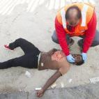 Un miembro de la Cruz Roja atiende a un inmigrante desmayado en el suelo (12 de agosto).